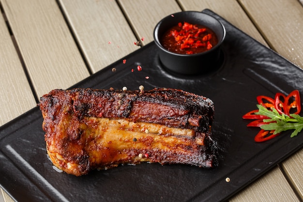 Costillas de cerdo a la parrilla y asadas con guindilla y salsa picante sobre piedra negra