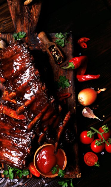 Foto costillas de cerdo a la parrilla con especias y verduras sobre un fondo de madera