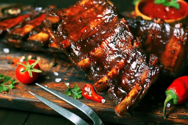 Costillas de cerdo a la parrilla con especias y verduras sobre un fondo de madera