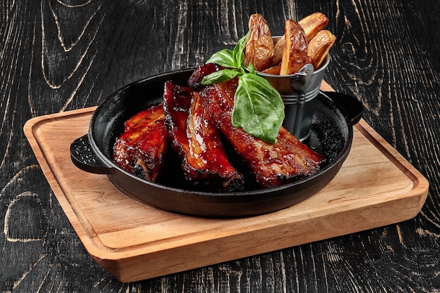 Costillas de cerdo a la parrilla con salsa barbacoa y gajos de papa