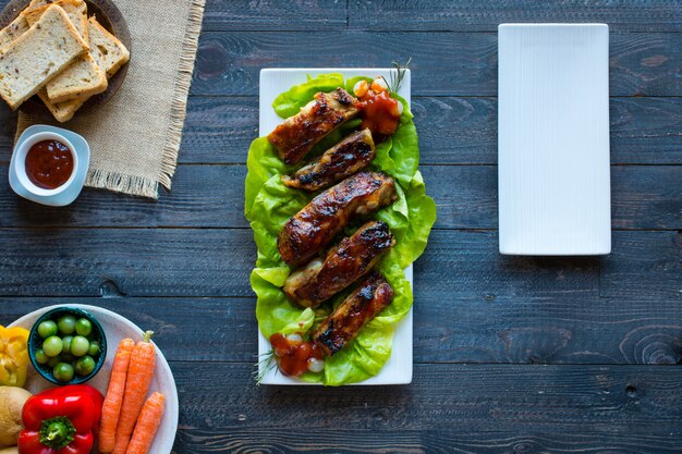 Costillas de cerdo a la parrilla con verduras en una mesa de madera