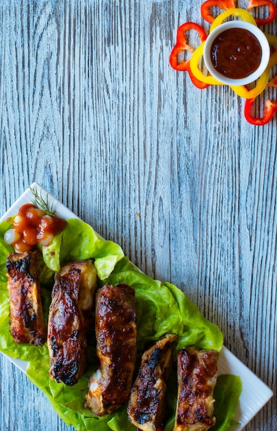 Costillas de cerdo a la parrilla con verduras sobre madera