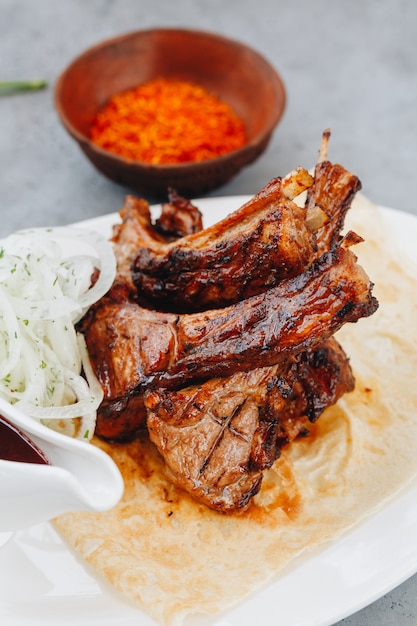 Costillas de cerdo y salsa de tomate en un plato blanco. Vista cercana