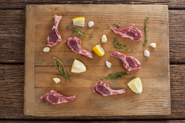 Costillas chuletas, limón y ajo sobre tabla de madera