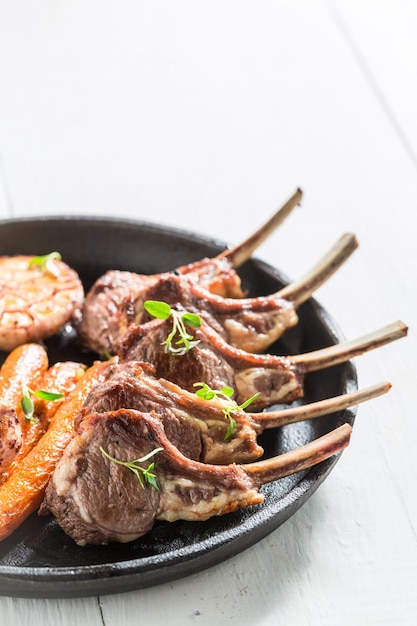 Costillas de cordero asadas con verduras en la mesa blanca