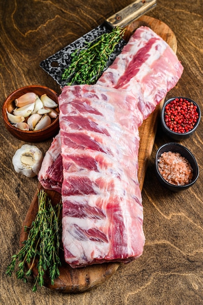 Costillas de cordero crudo fresco con especias en una tabla para cortar.