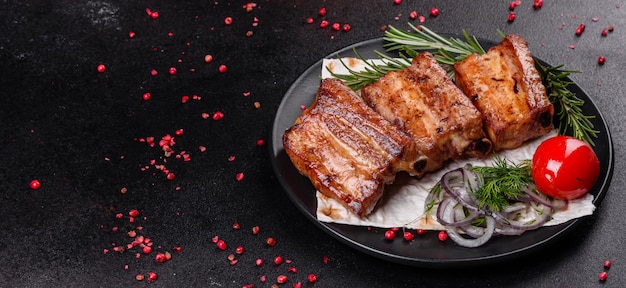 Costillas fritas con romero, cebolla, salsa sobre una superficie de hormigón. Mesa oscura Lugar para texto, copyspace