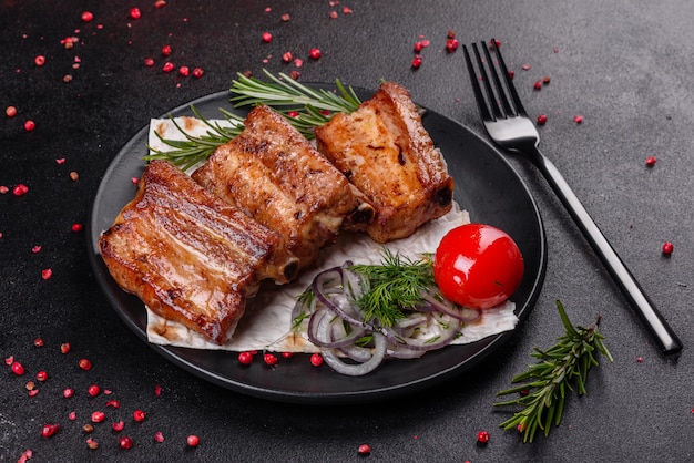 Costillas fritas con romero, cebolla, salsa sobre una superficie de hormigón. Mesa oscura Lugar para texto, copyspace