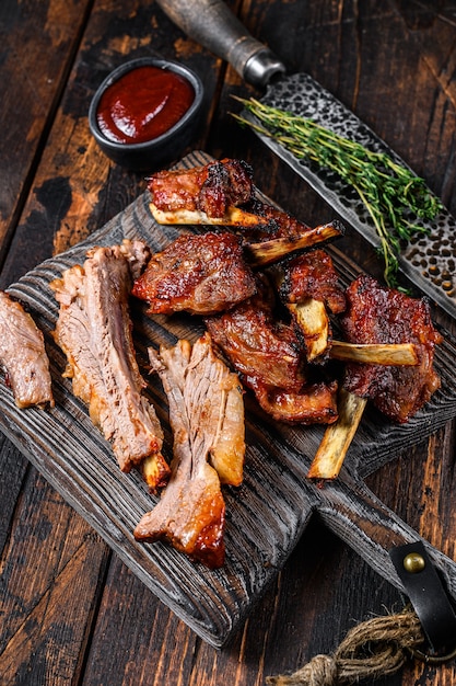 Costillas de lomo de ternera en rodajas a la parrilla a la parrilla sobre una tabla de cortar. Fondo de madera oscura. Vista superior.