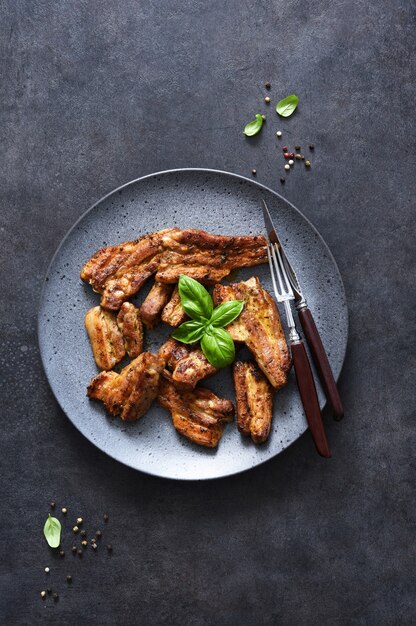 Costillas a la parrilla en un plato grande sobre una mesa de piedra negra