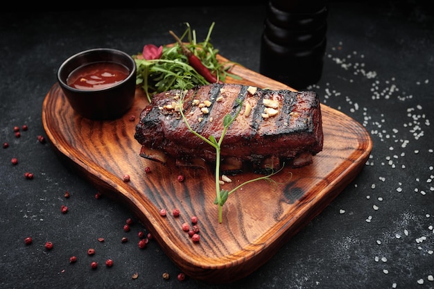 Costillas a la parrilla con salsa y hierbas sobre una tabla de madera