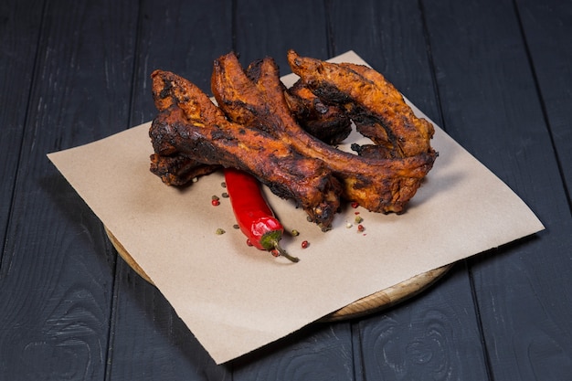 Costillas a la parrilla y salsa de tomate sobre fondo de madera negra