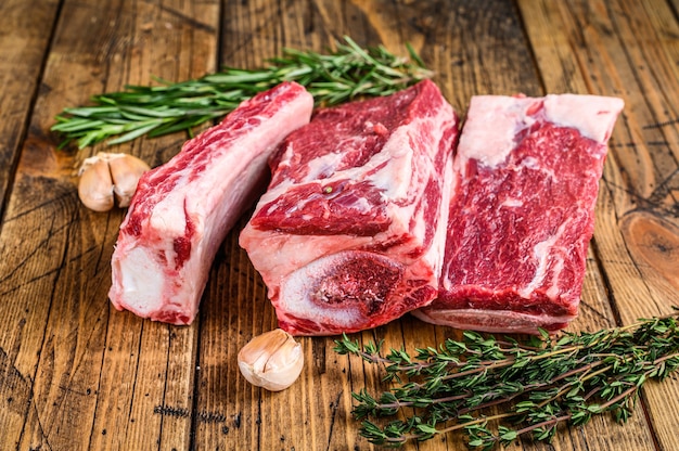 Costillas de ternera fresca sobre mesa de madera de carnicero. Fondo de madera. Vista superior.