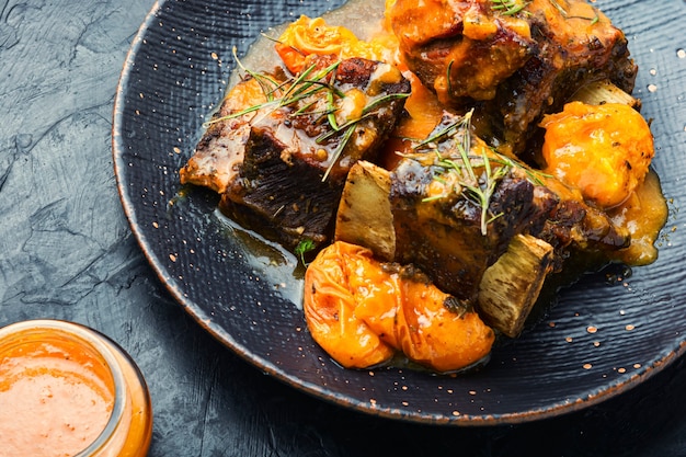 Costillas de ternera guisadas en albaricoques. Carne a la brasa con salsa de frutas