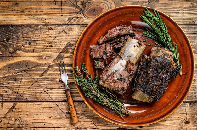 Costillas de ternera a la plancha con tomillo en un plato rústico. fondo de madera. Vista superior. Copie el espacio.