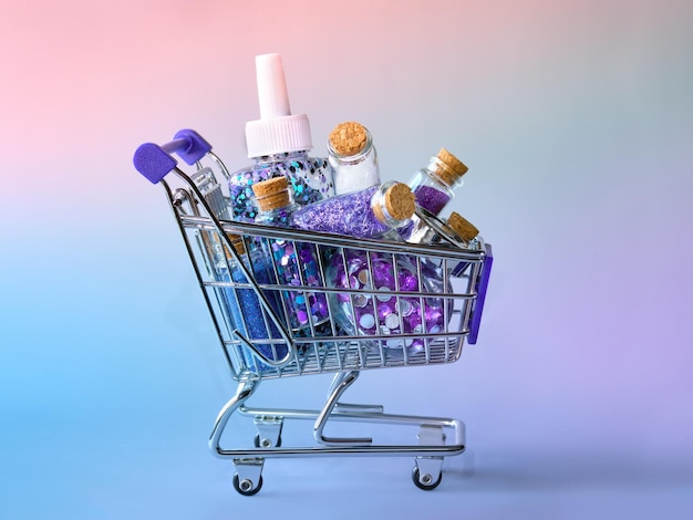 Costo de los productos de brillo Mini carrito de compras con varias botellas de brillo sobre fondo rosa azul neón abstracto