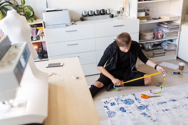 Foto costura de roupas e alfaiataria conceito designer de moda com pano e fita métrica fazendo novo vestido em casa estúdio ou oficina