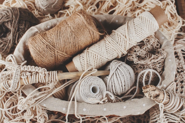 Costura, macramé, tejido de punto. Lana e hilo de colores naturales en cesta de mimbre. Pasatiempo de las mujeres.