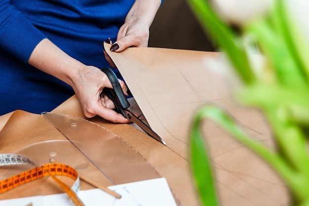 Una costurera corta un patrón con tijeras Preparación para coser el producto