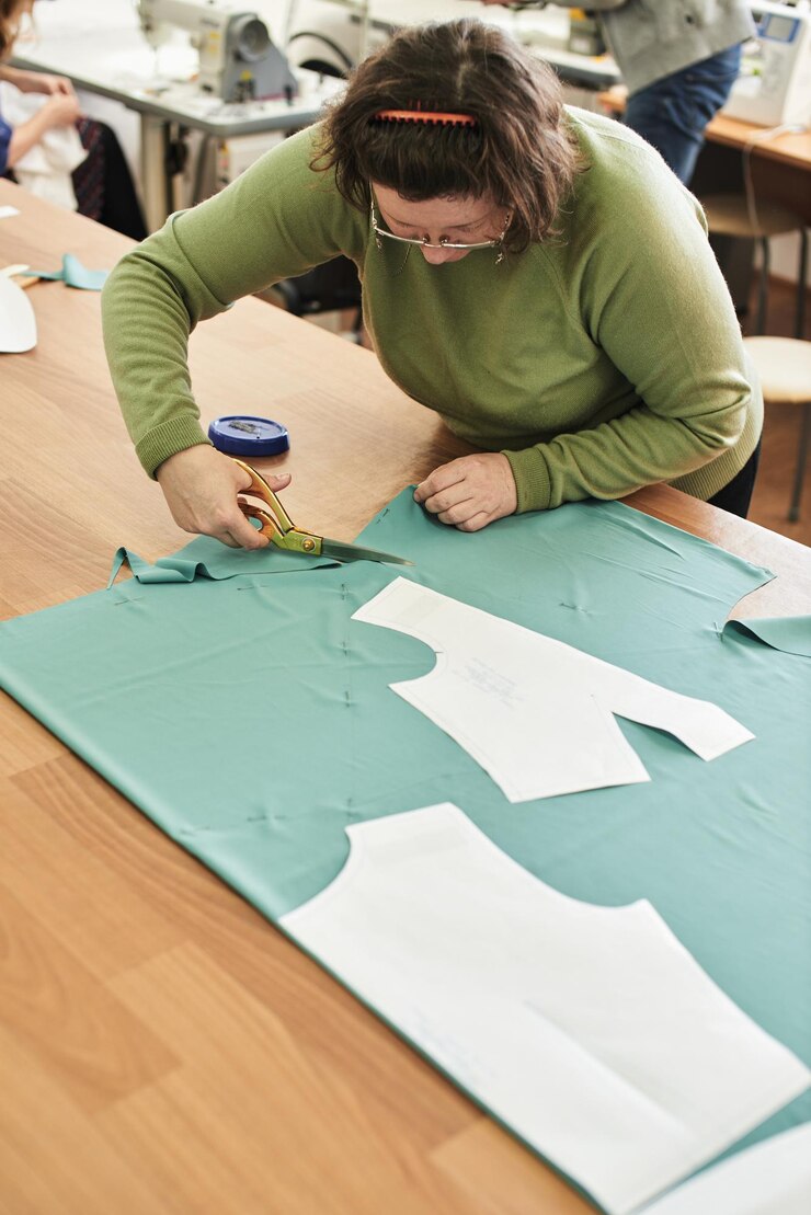 Foto la costurera corta las tijeras de tela sobre la mesa.