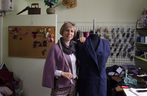 Una costurera cose manualmente un traje en un maniquí en un taller de costura