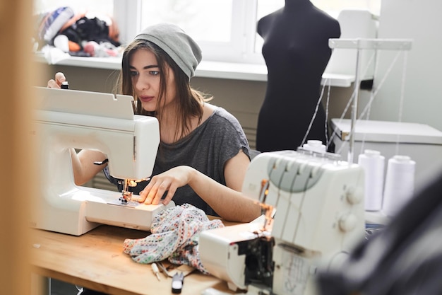 La costurera del cuello cose ropa en el estudio.