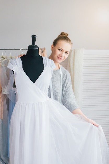 Costurera hace un vestido que se ajusta al maniquí