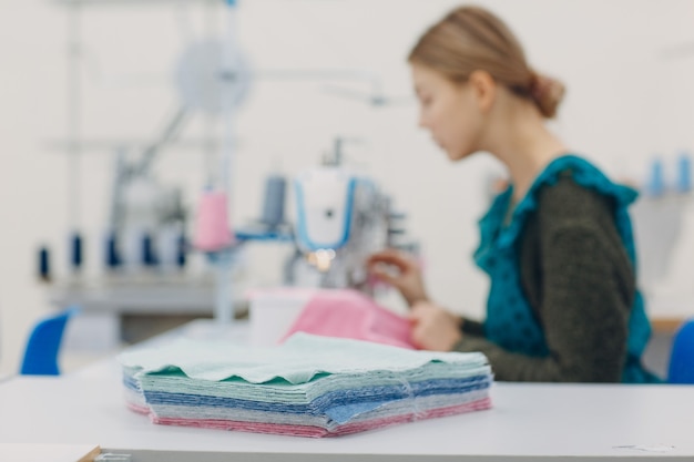 Costurera hermosa joven cose en la máquina de coser en la fábrica.