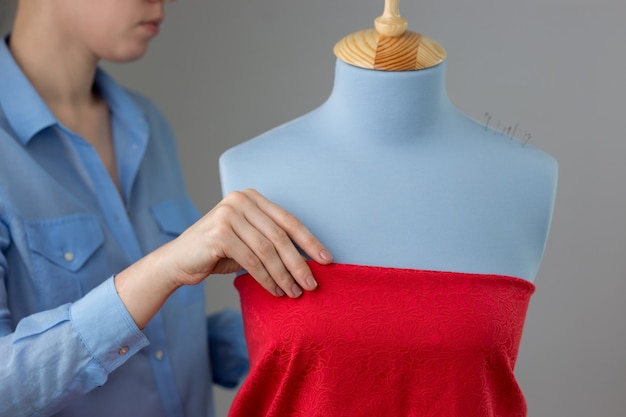 Costurera midiendo tela hermosa en maniquí de sastre azul en su taller.