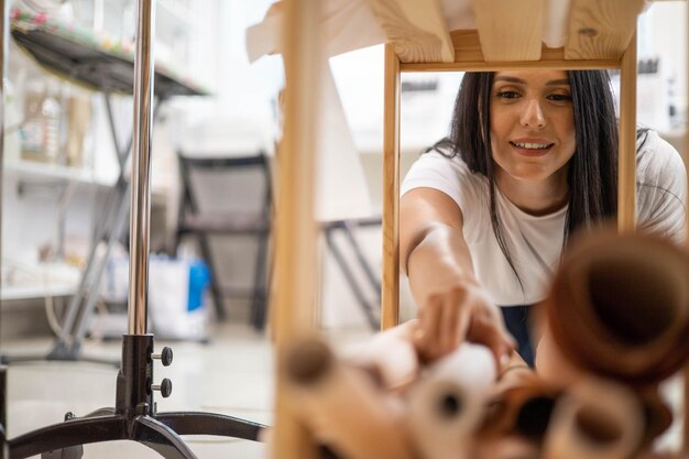 Costurera de mujer sonriente limpieza en taller de costura poniendo muestra de patrón de papel en caja de madera