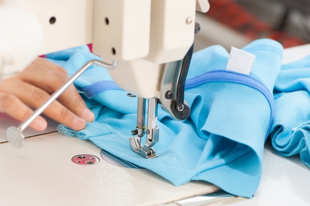 Costurera de primer plano en la máquina cose ropa en una fábrica de ropa