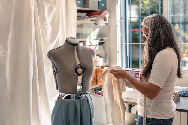 Costurera revisando un trozo de tela para ponerlo en un maniquí