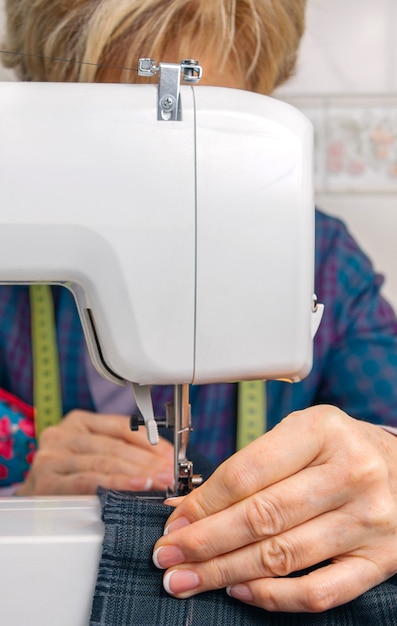 Costurera Senior mujer trabajando con prendas de vestir en una máquina de coser