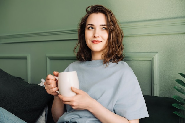 Foto cosy tea time nahaufnahme einer frau, die tee auf einem sofa in einem wohnzimmer genießt entspannte häusliche szene