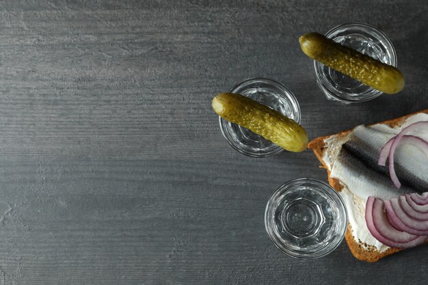 Cotas de vodka e petiscos saborosos em fundo escuro de madeira