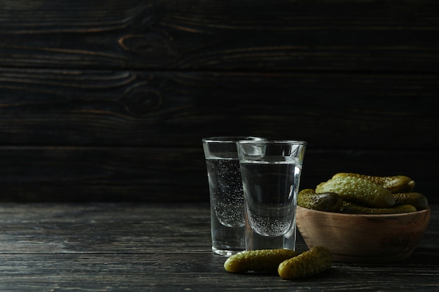 Cotas de vodka e pickles em fundo de madeira