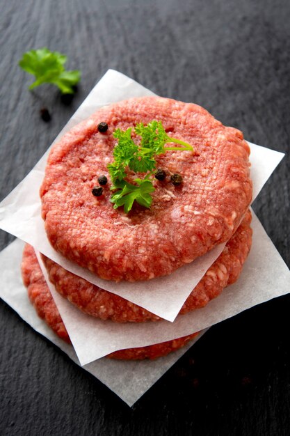 Cotlets de carne roja cruda, cocinando hamburguesas. Carne roja picada sobre fondo negro