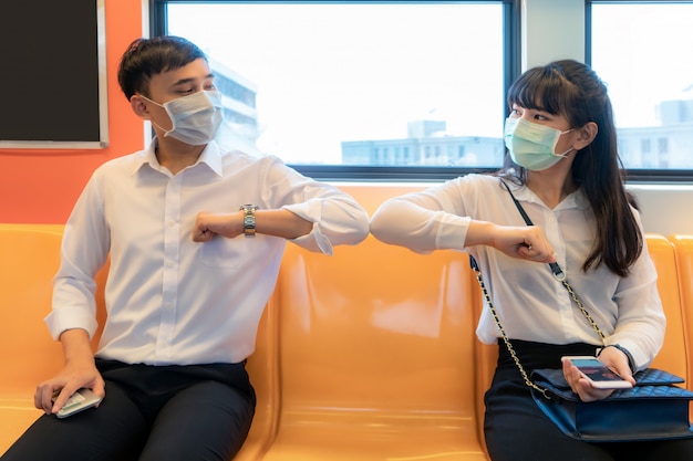 Cotovelo é uma nova saudação para evitar a disseminação do coronavírus Dois amigos de negócios asiáticos se encontram no metrô.