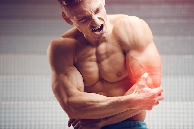 Cotovelo ferido Jovem atleta musculoso bonito com dor de cotovelo Conceito de fitness e saúde esportivo