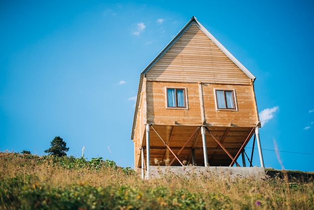 Cottage in der Nähe eines Kiefernwaldes mit blauem Himmel und Wiese