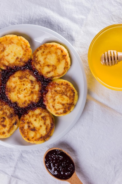 Cottage-Käse-Pancakes mit Marmelade auf weißem Teller Pancakes mit Hüttenkäse und Honig auf weißer Serviette