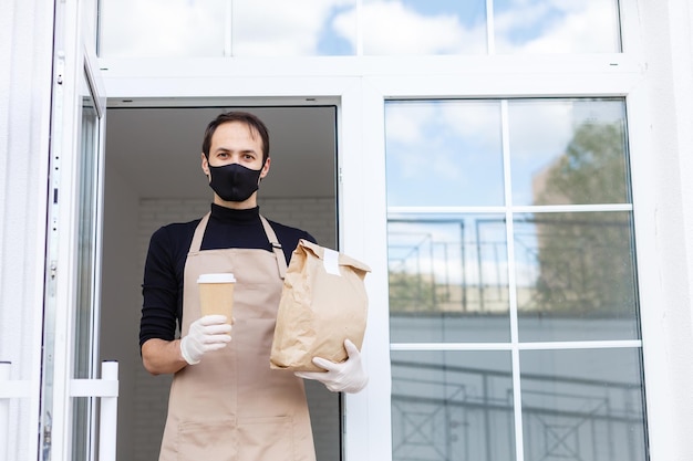 Courier com máscara protetora e luvas médicas entrega comida para viagem. Serviço de entrega em quarentena, surto de doença, condições de pandemia de coronavírus covid-19.