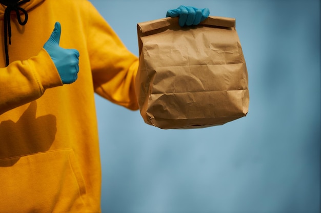 Foto courier em um fundo azul com um pacote nas mãos entrega de alimentos courier com um pacote fechado