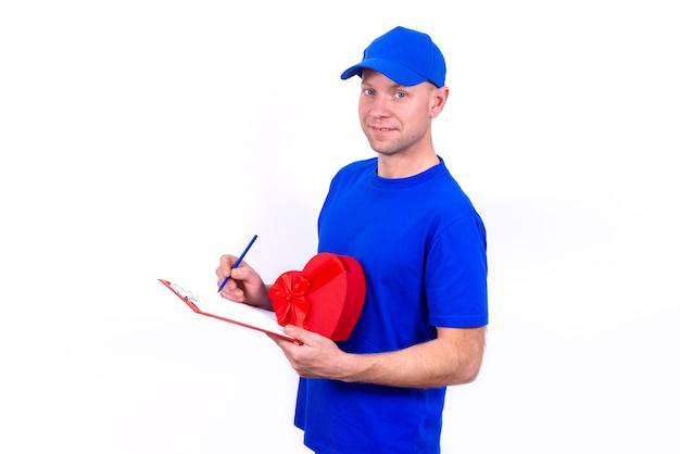 Courier en uniforme azul tiene caja de regalo roja en forma de corazón para el Día de San Valentín y comprueba el pedido en