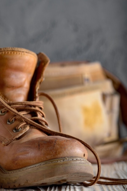 Couro amarelo usado botas de trabalho e cinto de ferramentas em closeup de fundo de madeira. Lugar para texto