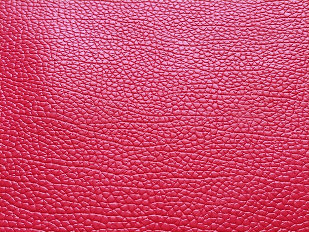 Couro vermelho falso Ranhuras e elevações separadas na superfície de uma bolsa ou sapato Reflexo da luz Acessório de moda feito de pele de porco falsa Closeup