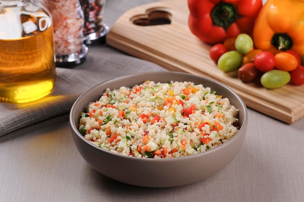 Foto couscous mit gemüse in einer rustikalen schüssel, umgeben von tomaten, paprika und einem glas olivenöl marokkanischer couscous selektiver fokus