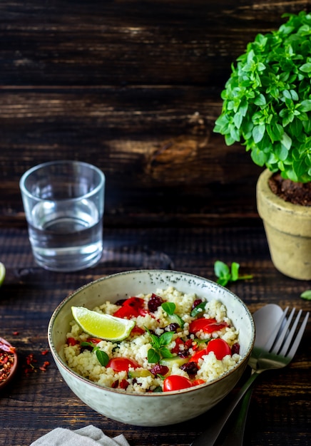 Foto couscous-salat mit tomaten, paprika, zucchini und preiselbeeren. vegetarisches essen. diät. gesundes essen.