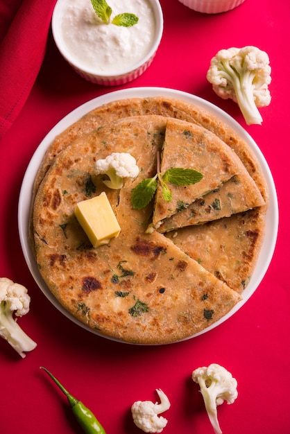 Couve-flor recheada ou Gobi Paratha é um pão achatado indiano. menu de café da manhã ou almoço favorito no norte da Índia, servido sobre um fundo sombrio com requeijão e ketchup de tomate em uma tigela