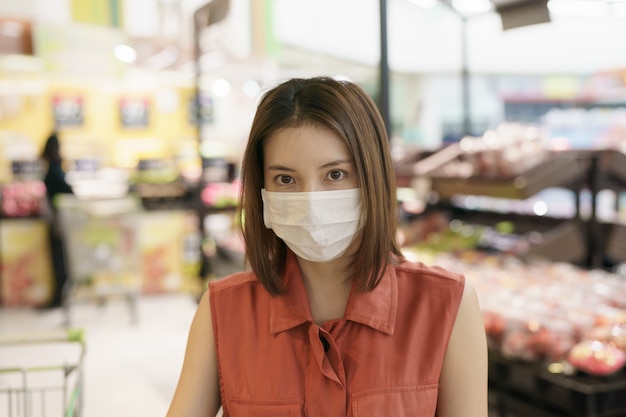 Covid-19-Ausbruch. Frau in der medizinischen Schutzmaskenpanik, die Lebensmittel kauft. Angst vor Coronavirus.